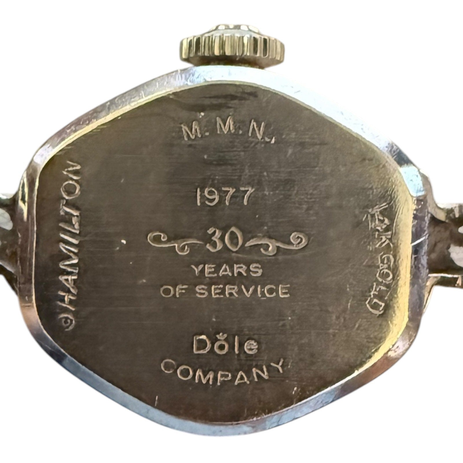 Back of a watch with engraved text celebrating 30 years of service at Dole Company in 1977.