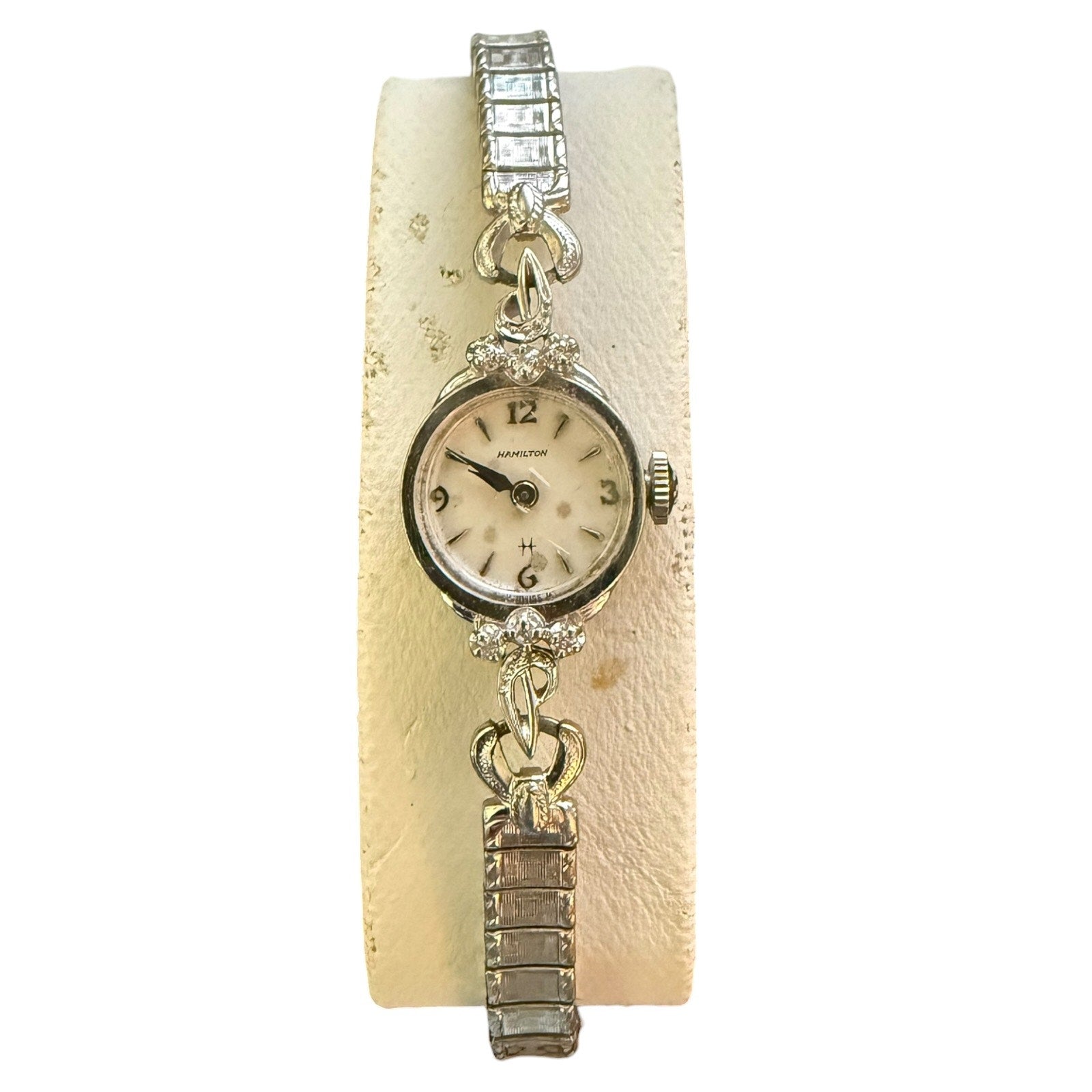 Vintage watch with decorative band on a textured beige background