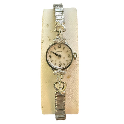 Vintage watch with decorative band on a textured beige background