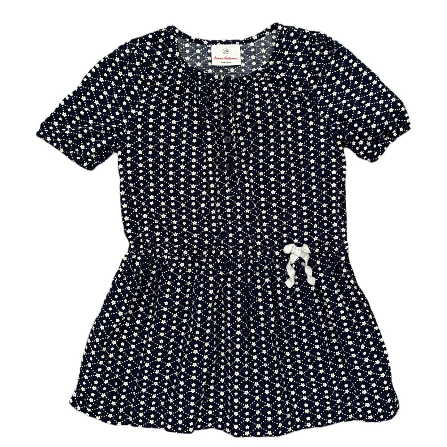 A short-sleeve peplum-style dress with an allover white floral print on a dark navy background, featuring a gathered waist and a small white bow detail on the front.