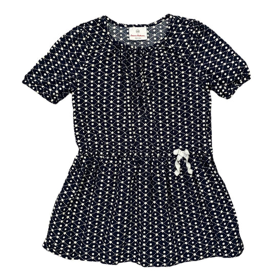 A short-sleeve peplum-style dress with an allover white floral print on a dark navy background, featuring a gathered waist and a small white bow detail on the front.