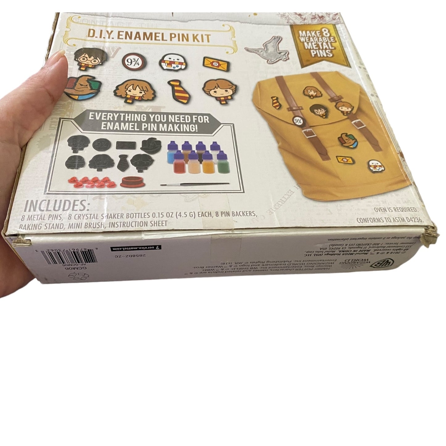 DIY Enamel Pin Kit packaging held by a hand on a white background