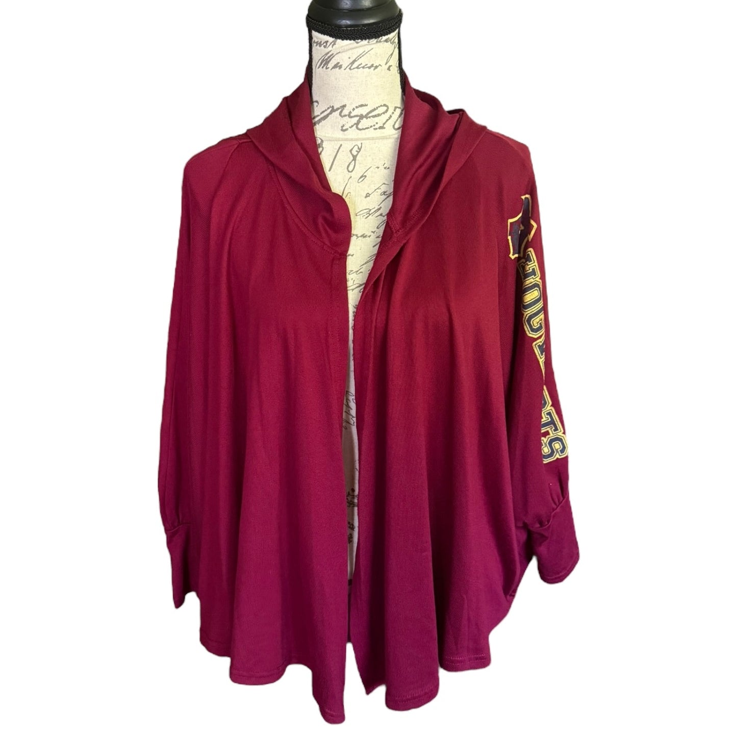A red light jacket with a split neckline and a gold and black graphic on the sleeve, displayed on a vintage-style mannequin torso against a white background.
