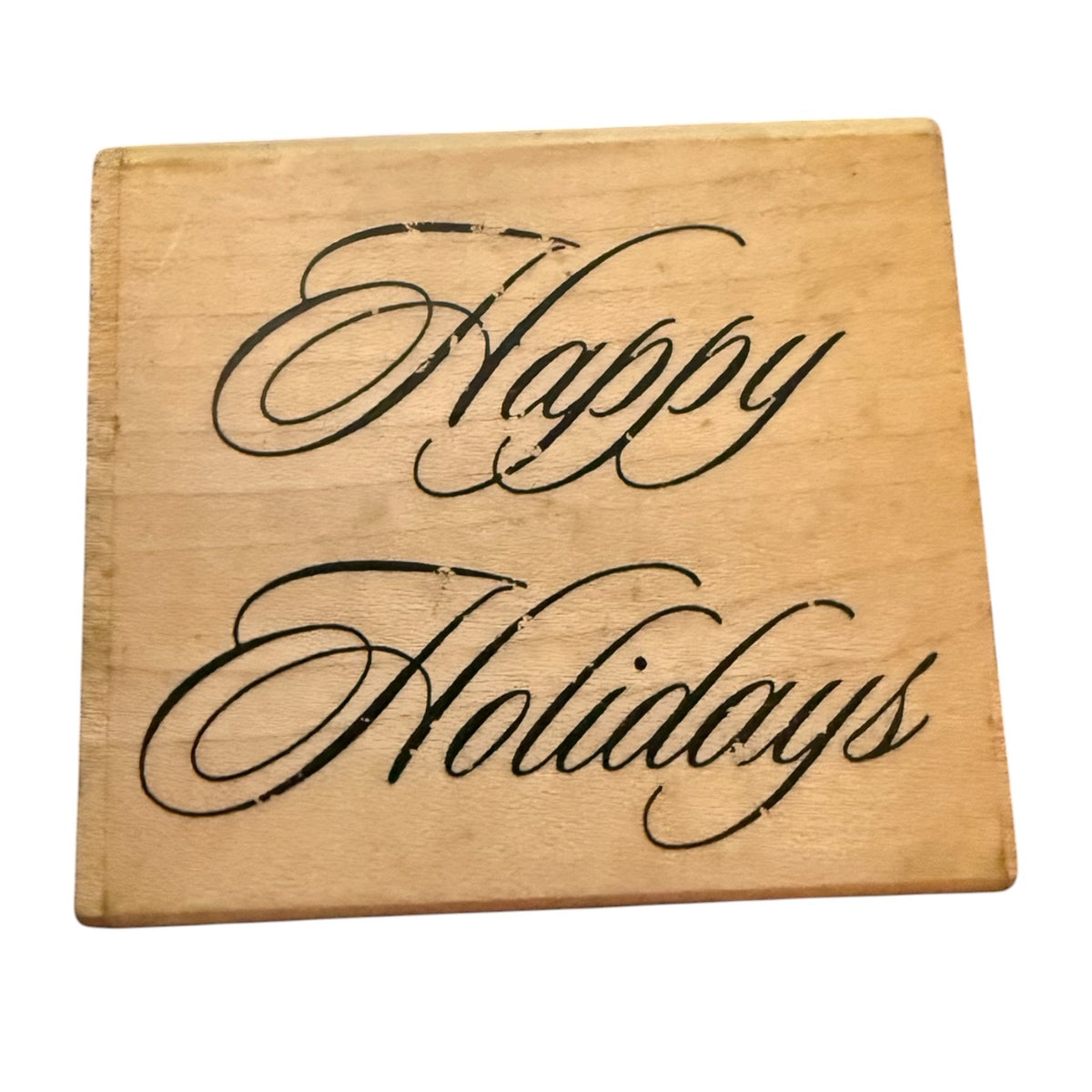 A square wooden block with 'Happy Holidays' written in black cursive script, shown on a plain white background.