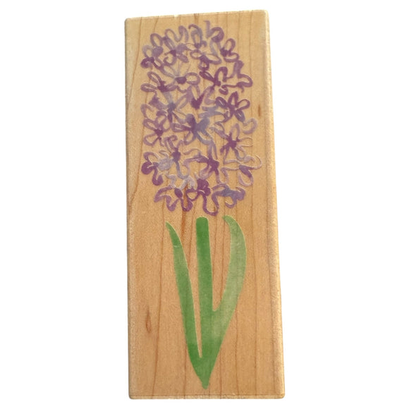 Wooden stamp with a purple flower and green stem on a white background