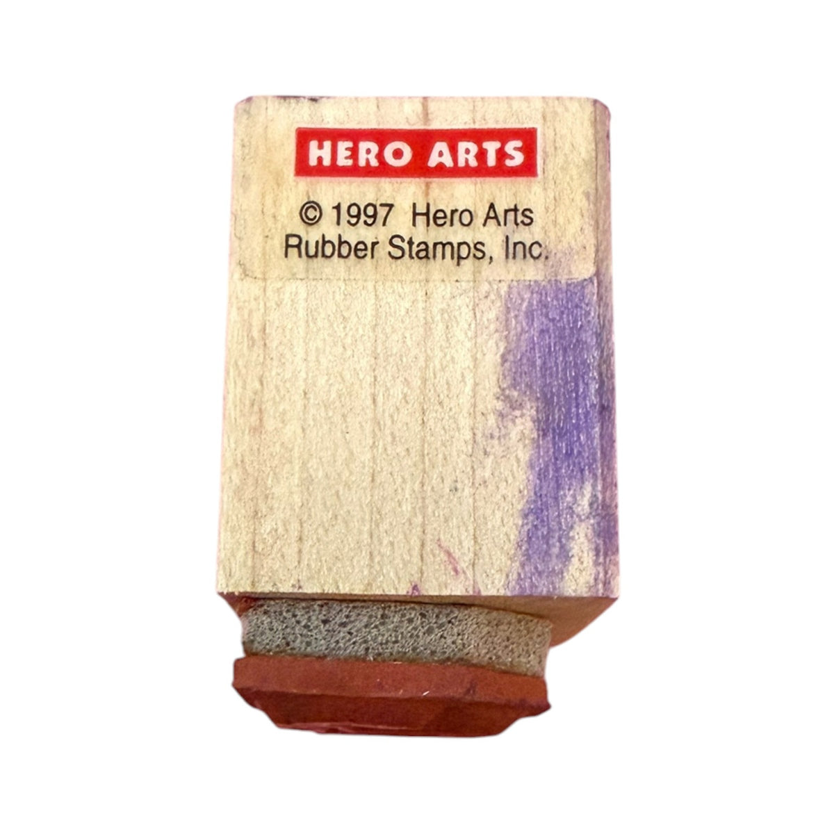Side view of a rubber stamp with HERO ARTS and a purple stain on a white background