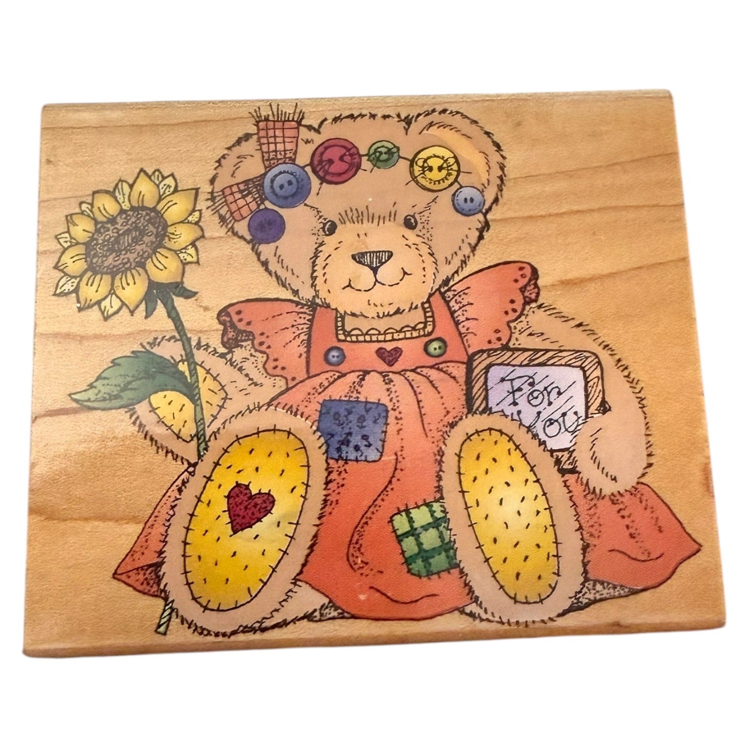 Wooden stamp with a teddy bear and sunflower design on a white background