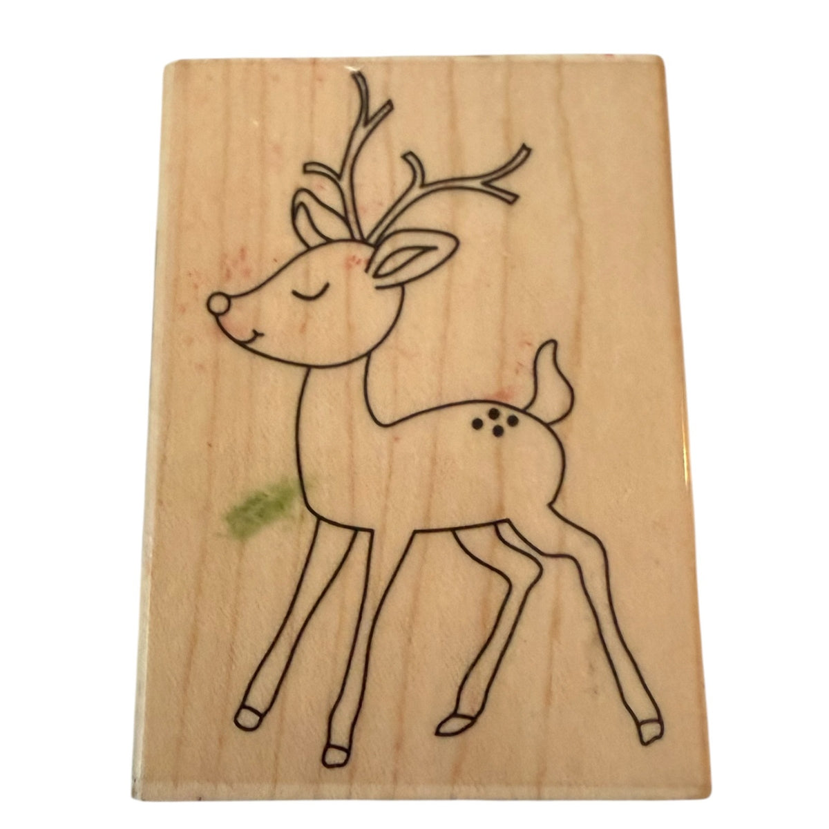 A wooden rubber stamp featuring a simple black line drawing of a reindeer with closed eyes and small antlers, shown on a plain white background.