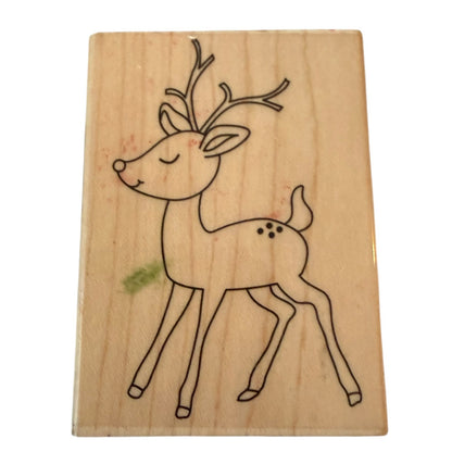 A wooden rubber stamp featuring a simple black line drawing of a reindeer with closed eyes and small antlers, shown on a plain white background.