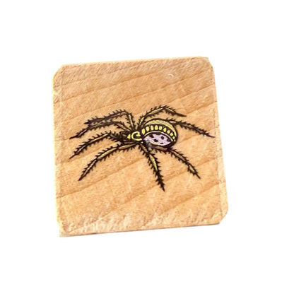 Small wood block with a spider design on a white background