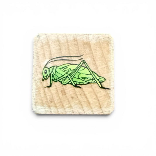 Rubber stamp with a green grasshopper design on a wooden block