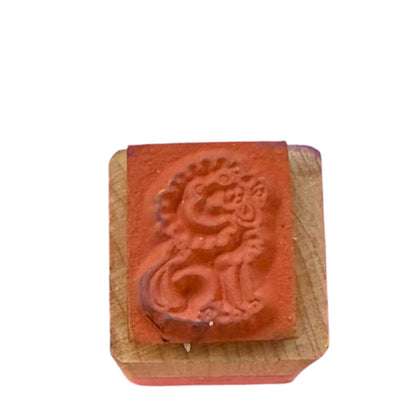 Red rubber stamp on a wood block with a white background. 