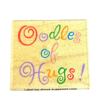 Stamp with Colorful text 'Oodles of Hugs!' on a yellow label with a white background