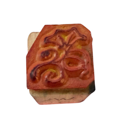 A wooden block with a rubber stamp of a floral design, shown on a plain white background.