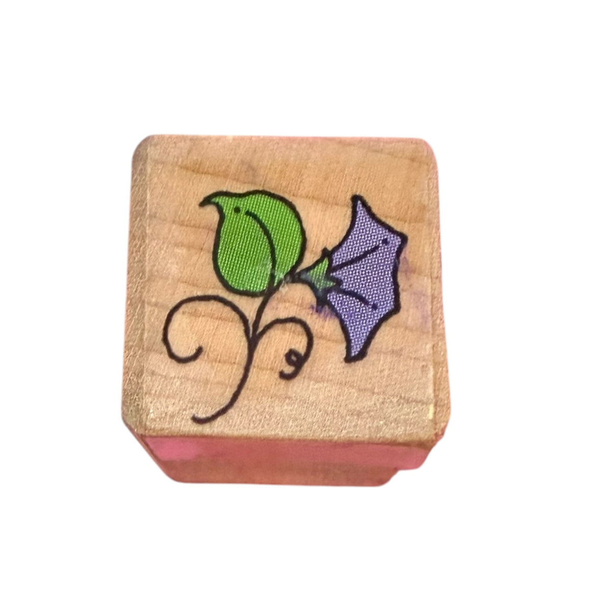 A wooden rubber stamp featuring a illustration of a green and purple flower with a black vine, set against a plain white background.