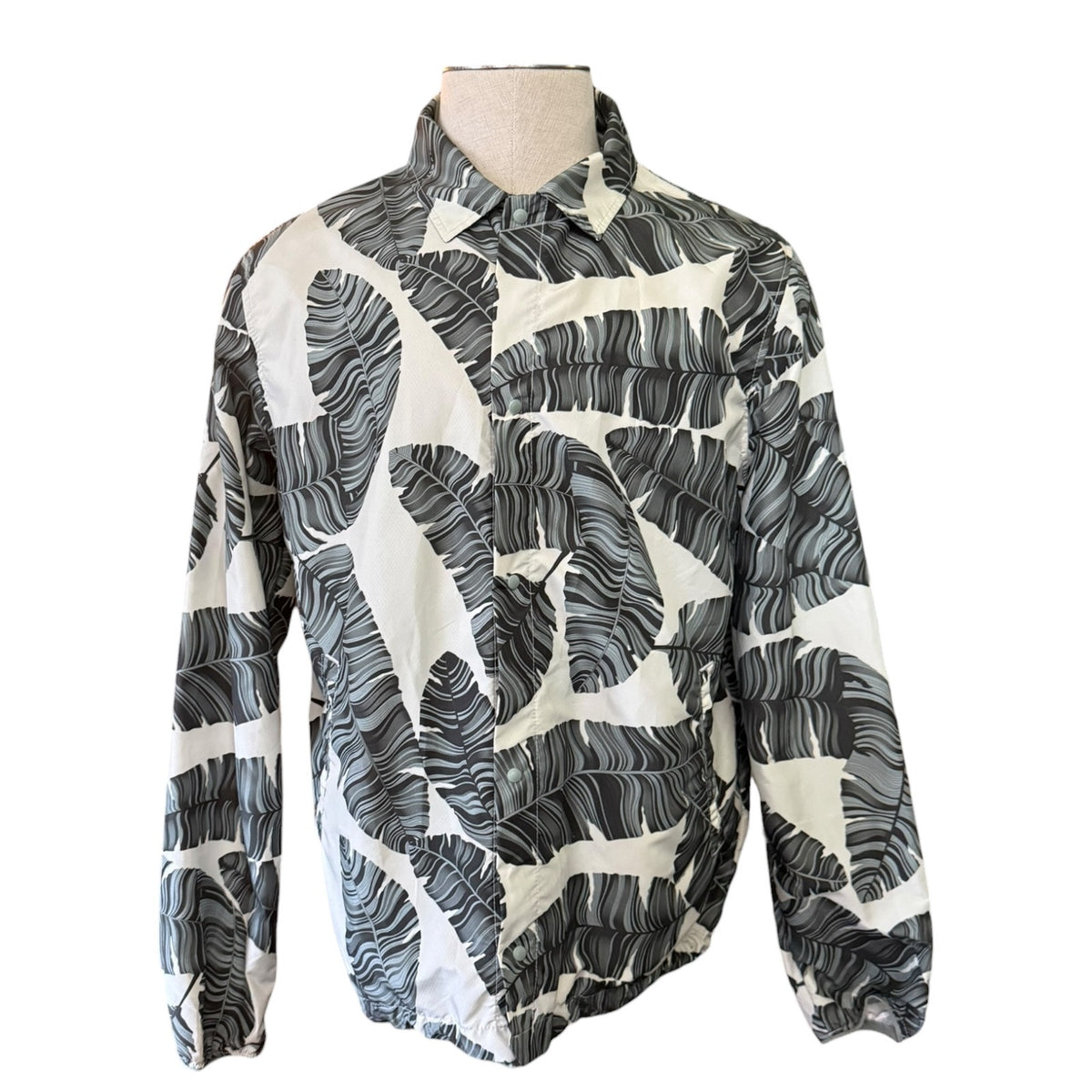 Mannequin wearing a patterned jacket with palm leaf design on a white background