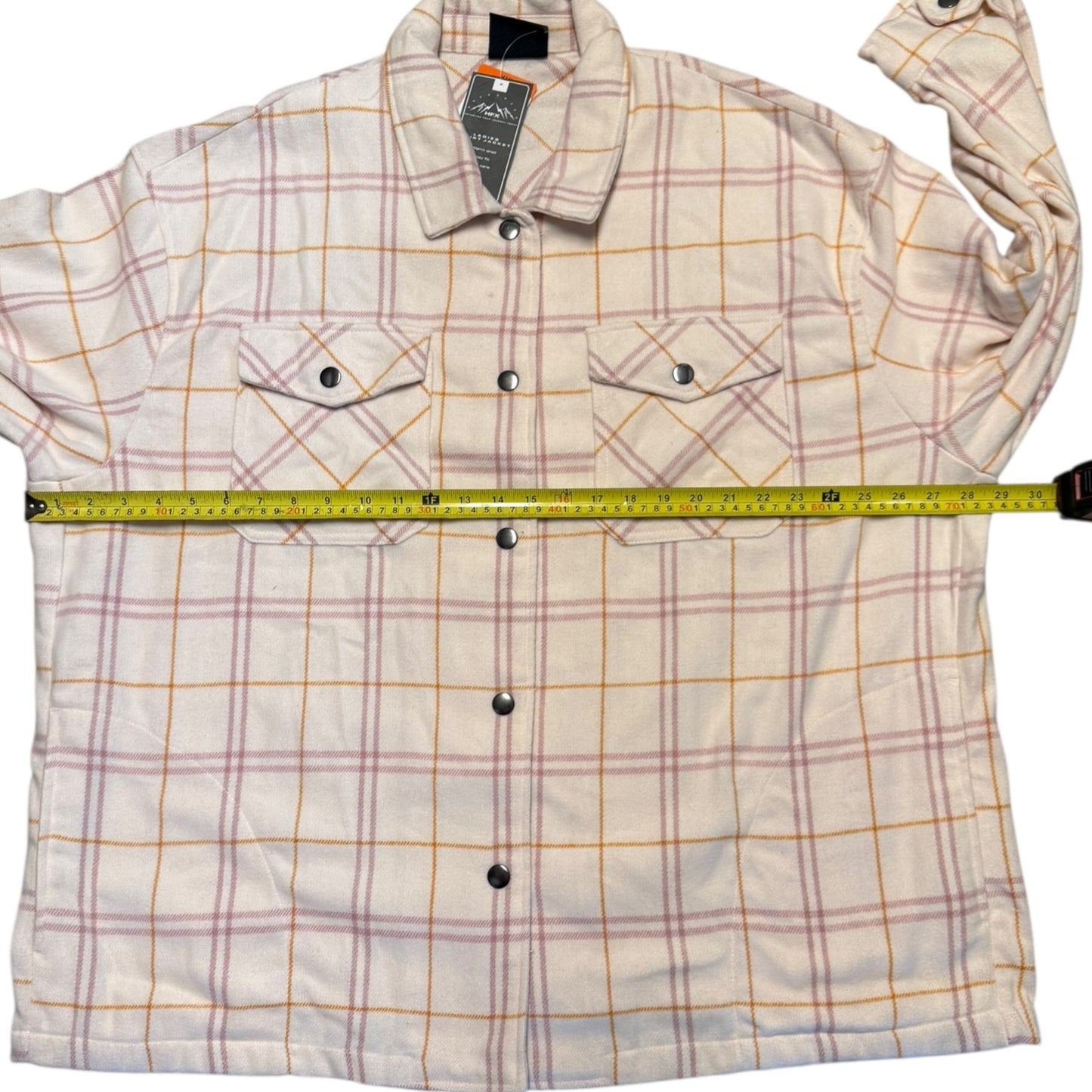 Plaid jacket with a measuring tape laid across it on a white background