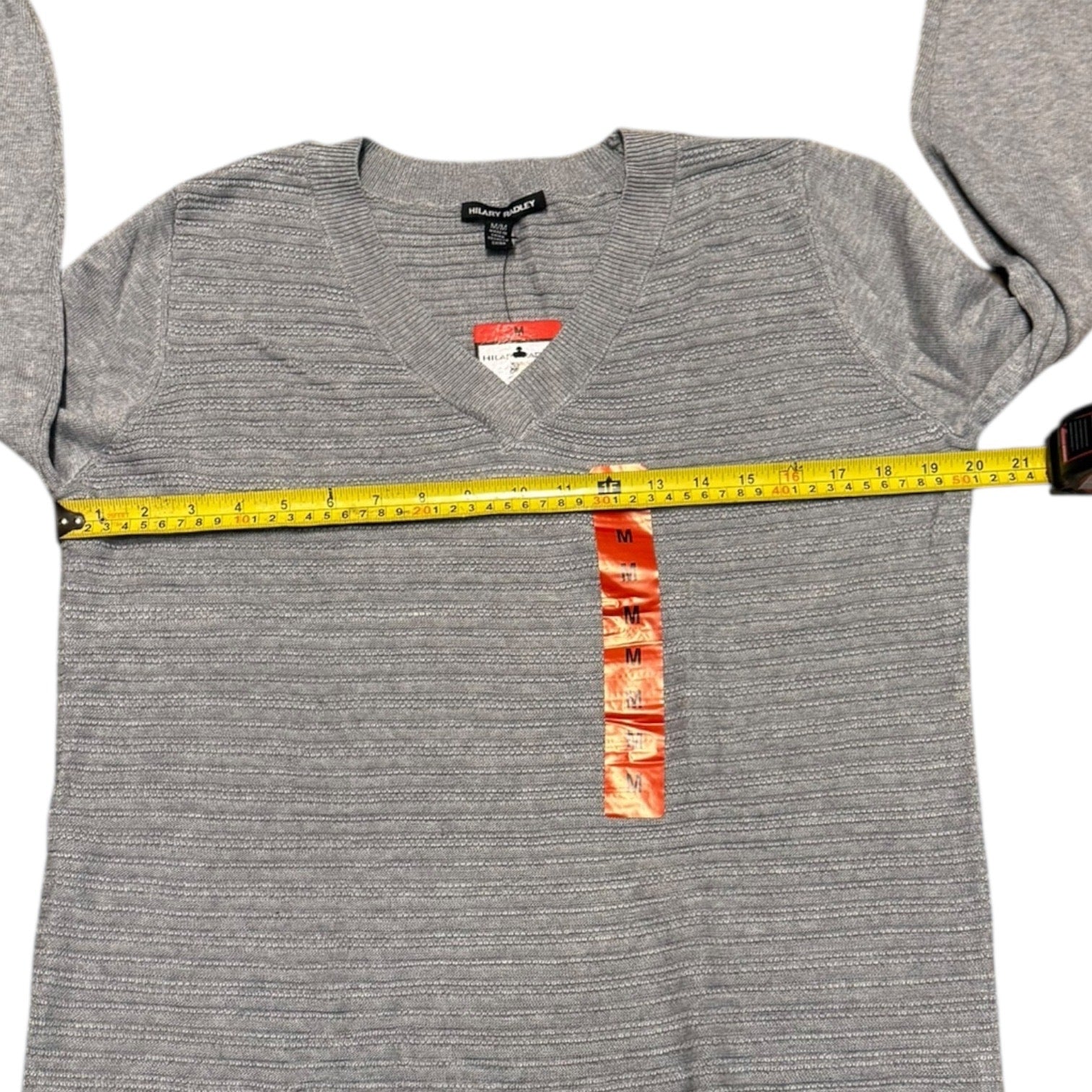 Gray long-sleeve sweater with a measuring tape on a white background