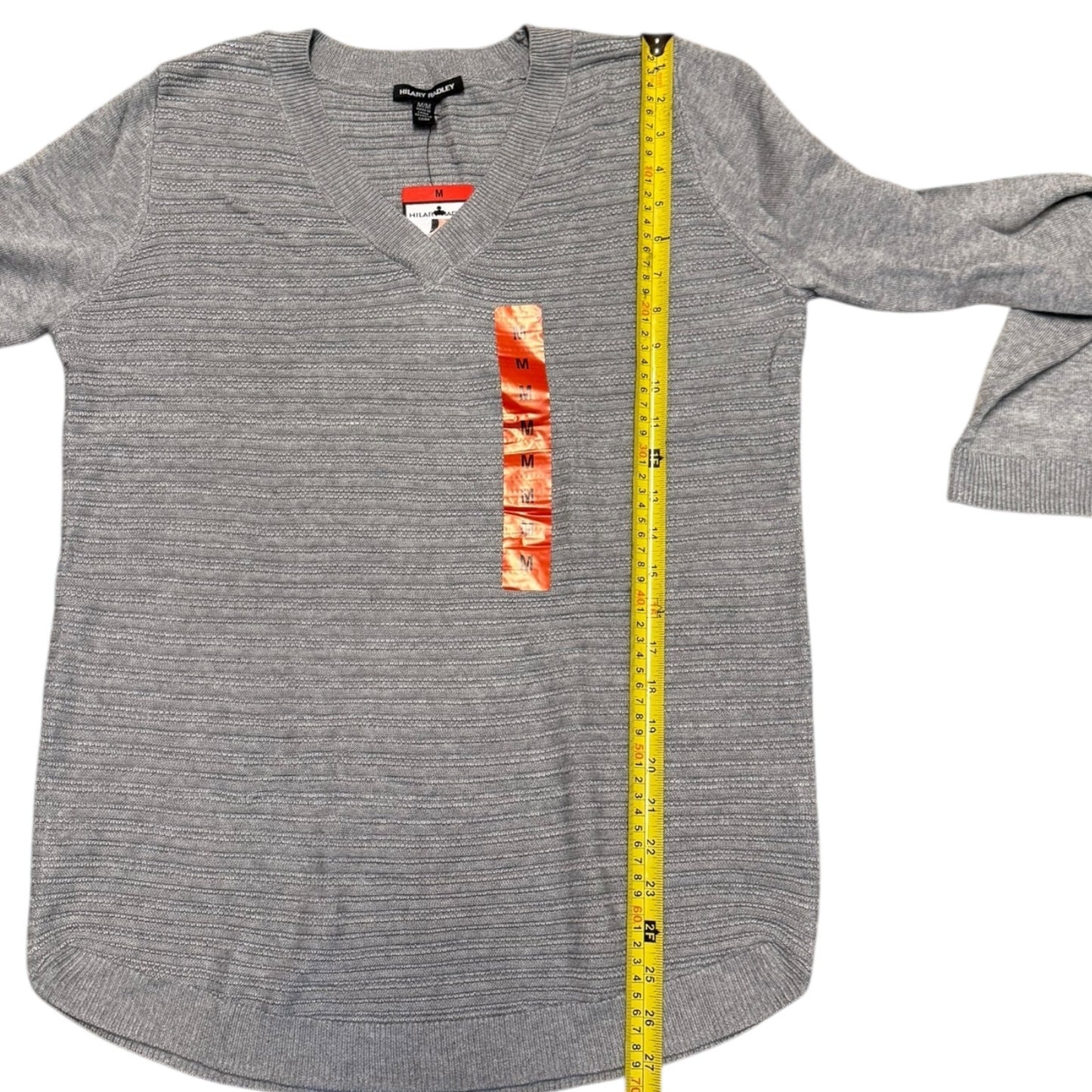 Gray long-sleeve sweater with a measuring tape on a white background