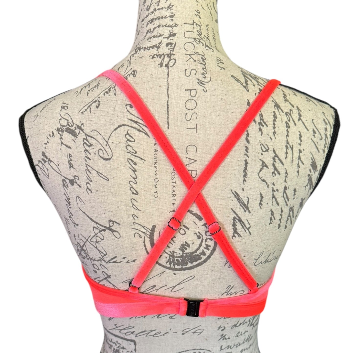 Neon pink strappy top on a mannequin with a vintage-style script background