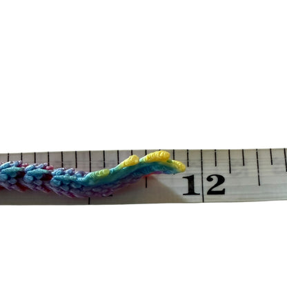 Colorfuldragon tail next to a measuring tape on a white background