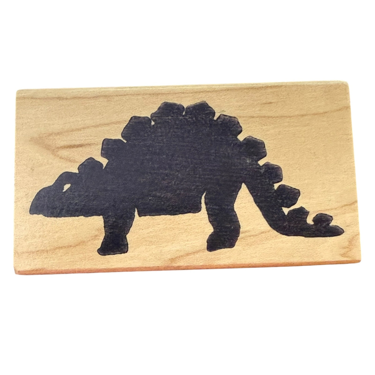 A rectangular wooden stamp with a black silhouette of a Stegosaurus dinosaur, shown on a plain white background.