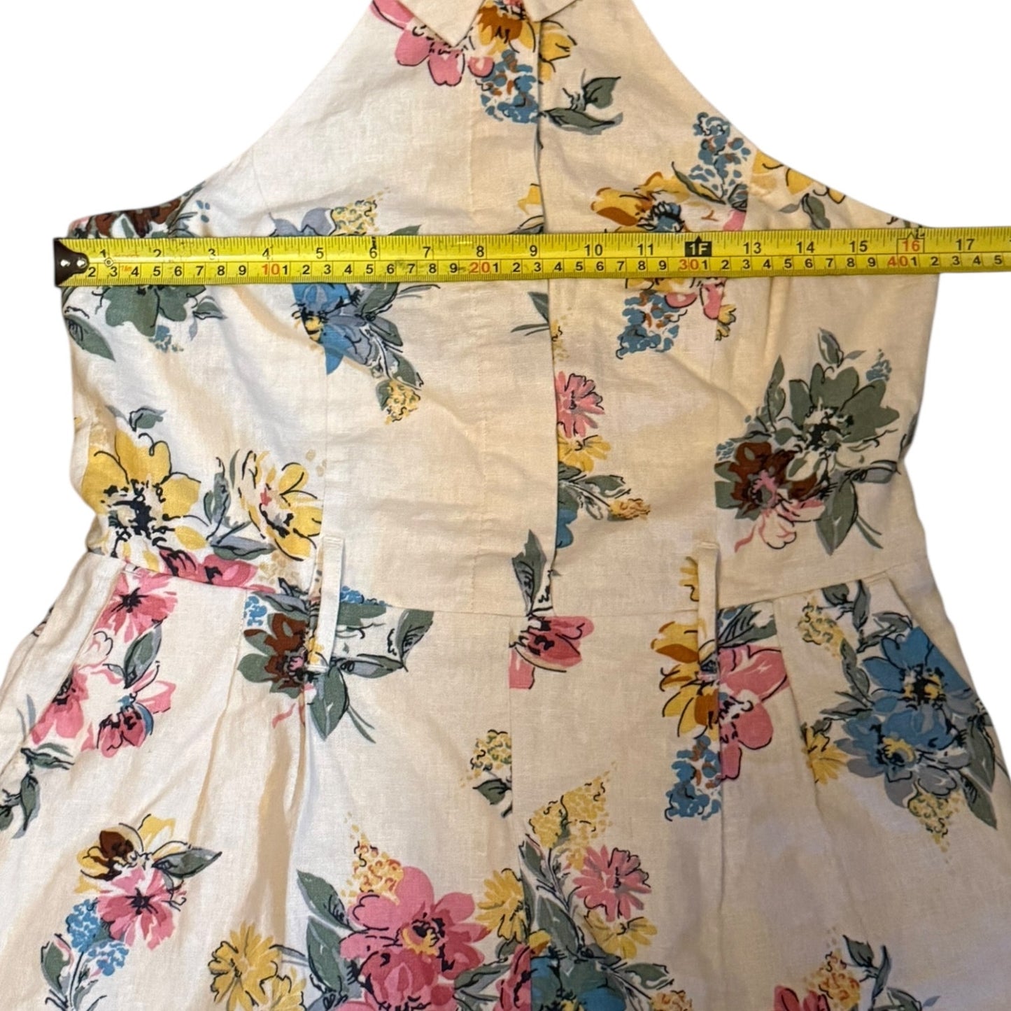 Floral-patterned jumper with a measuring tape indicating its width.