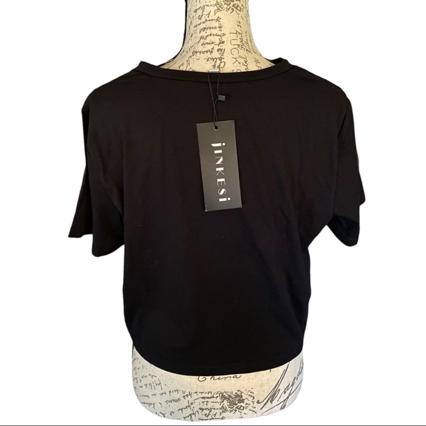 Back of Black t-shirt on a mannequin with a visible brand tag against a white background
