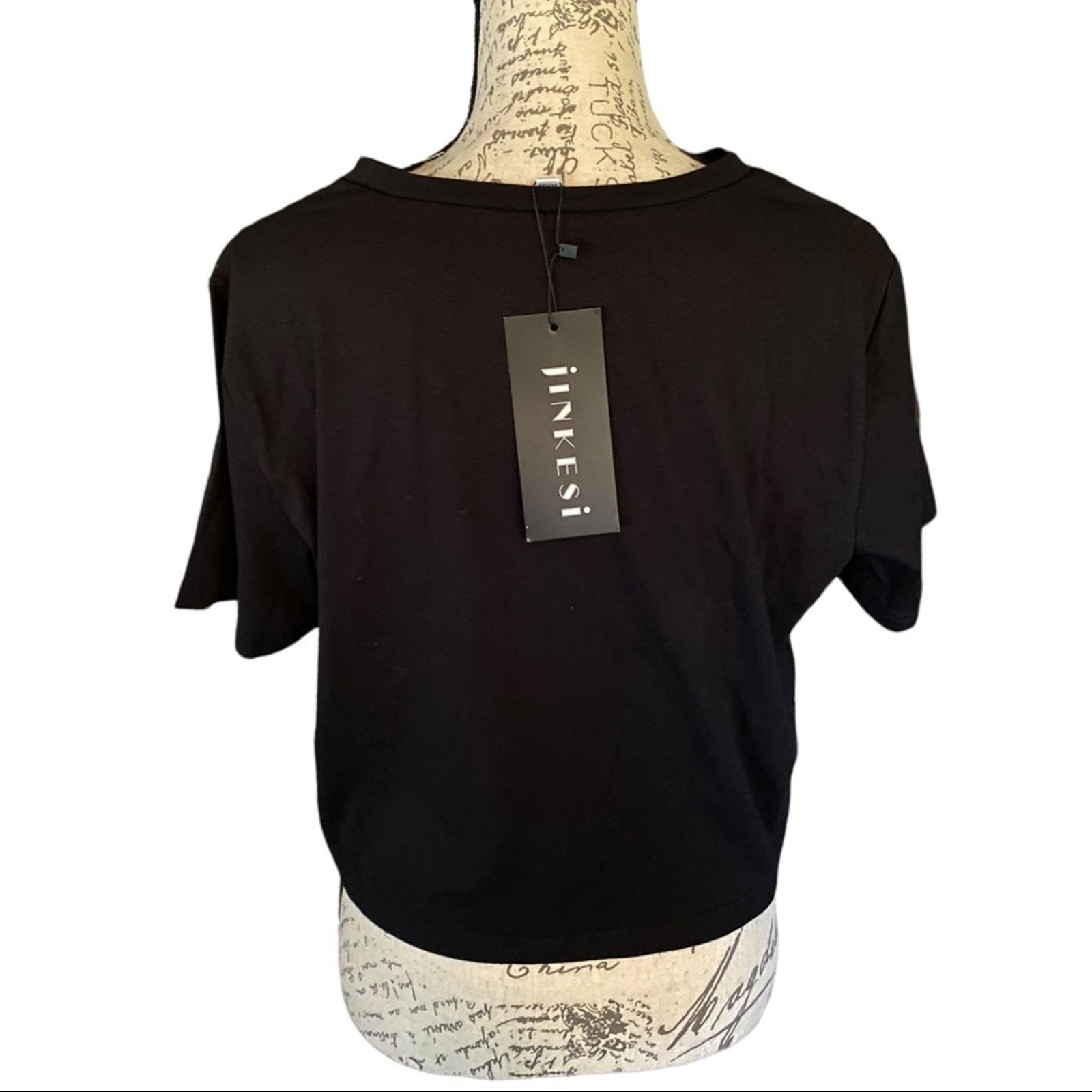 Back of Black t-shirt on a mannequin with a visible brand tag against a white background