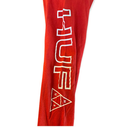 Sleeve of red shirt with white 'HUF' logo on a white background