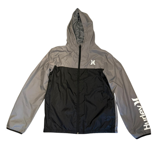 A colorblock hooded windbreaker jacket by Hurley, featuring a gray upper body and sleeves, a black lower body panel, a white logo on the left chest, and white script branding down the right sleeve, laid flat against a white background.