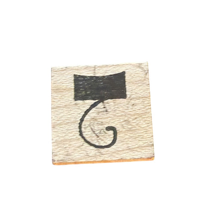 A square wooden stamp with a hook or the number 2 and a light beige wood grain background.