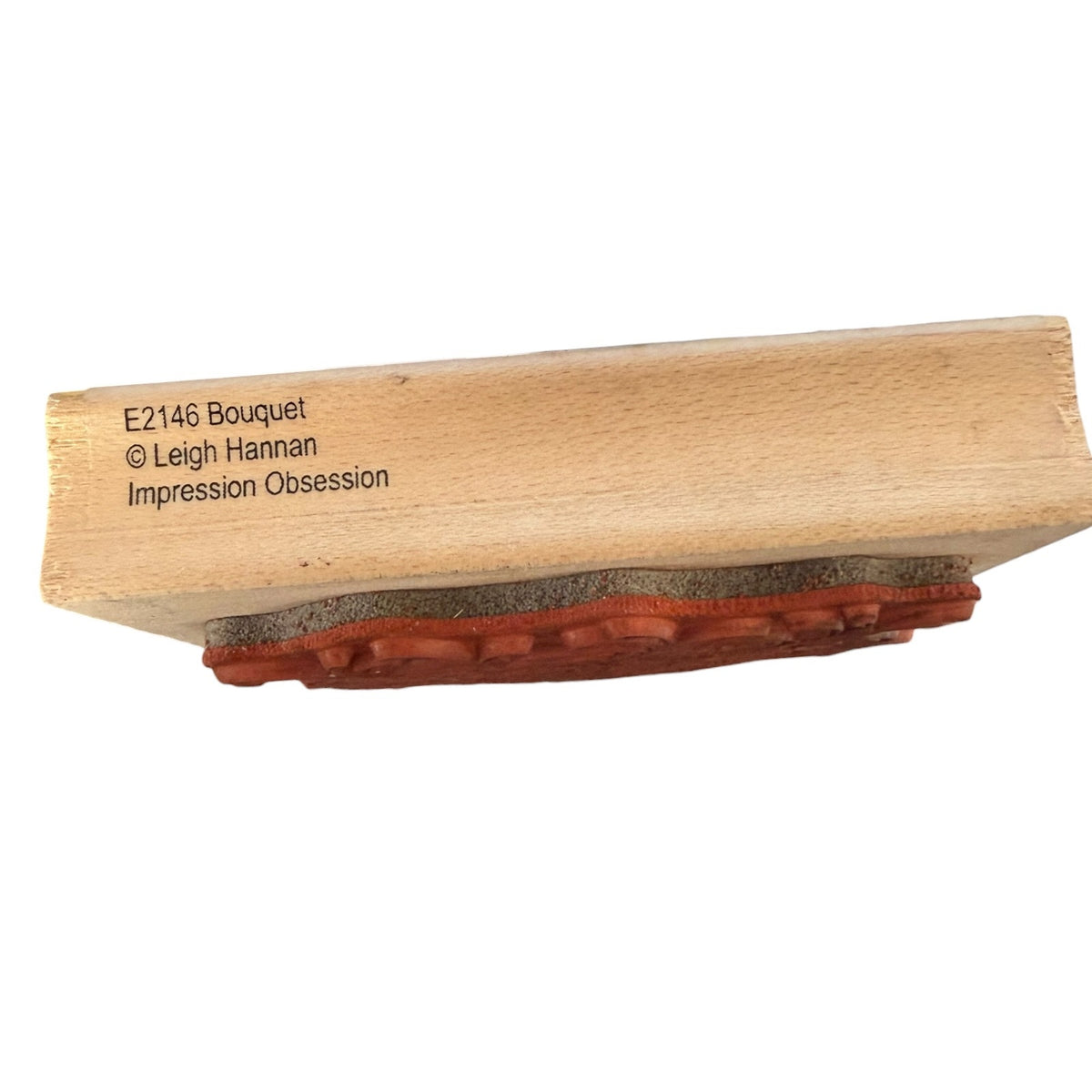 A wooden stamp block rubber stamp face and printed text reading 'E2146 Bouquet © Leigh Hannan Impression Obsession' on a plain white background.