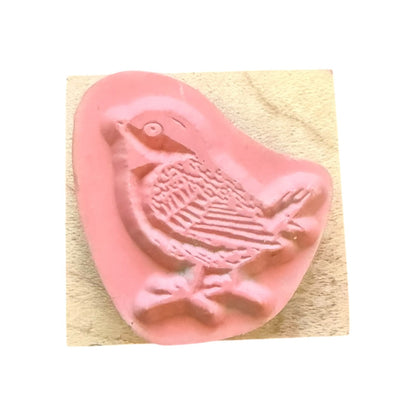 Pink bird-shaped stamp on a wood block with white background