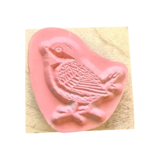Pink bird-shaped stamp on a wood block with white background