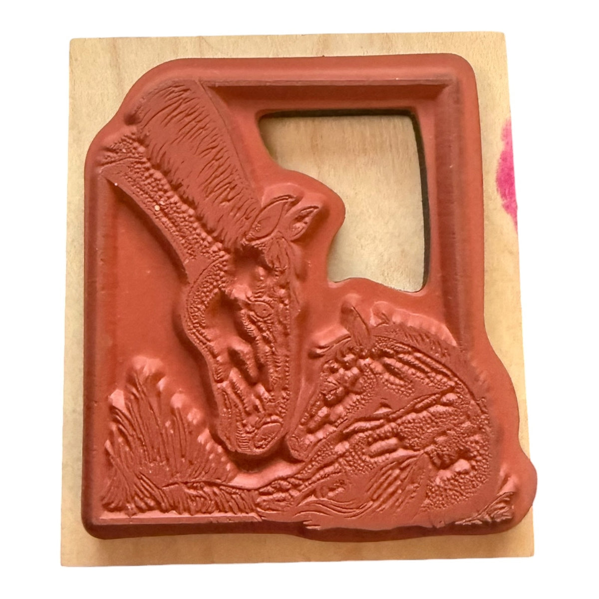 A wooden rubber stamp featuring rubber stamp design of a horses  shown on a light wood block against a white backgrond