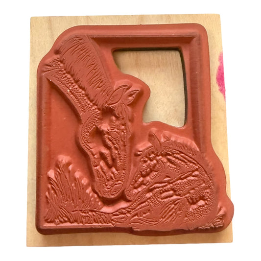 A wooden rubber stamp featuring rubber stamp design of a horses  shown on a light wood block against a white backgrond