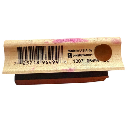 A wooden rubber stamp block with a barcode and product text printed on the top, shown against a plain white background.