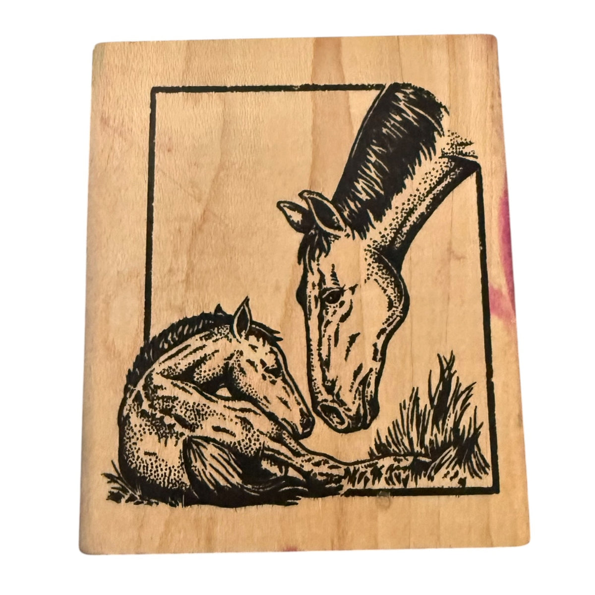 A rectangular wooden stamp block featuring a black ink illustration of a mare and foal, photographed against a plain white background.