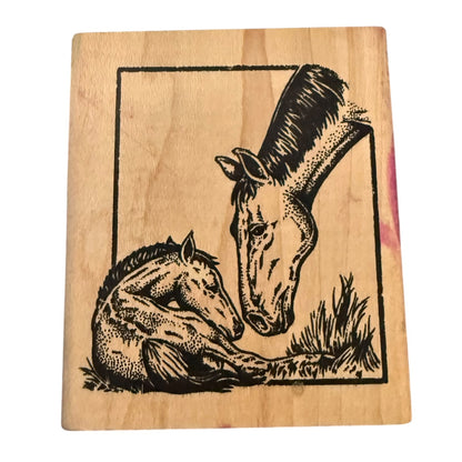 A rectangular wooden stamp block featuring a black ink illustration of a mare and foal, photographed against a plain white background.