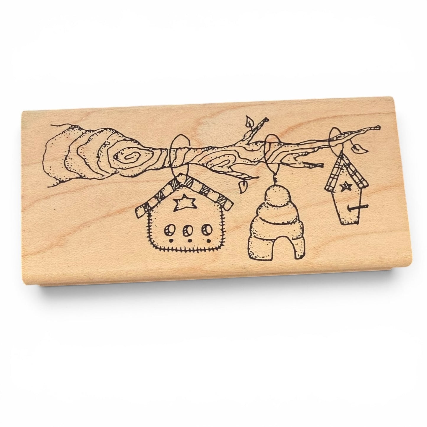 Wooden stamp with illustrations of a bee hive and birdhouse on a branch.