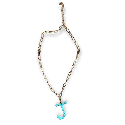 A gold-toned chain necklace with a dangling letter 'J' charm made of small turquoise beads, shown on a plain white background.
