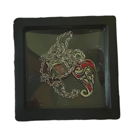 A necklace featuring silver-tone charms of Jack Skellington and Sally , displayed in a black box with a clear cover.