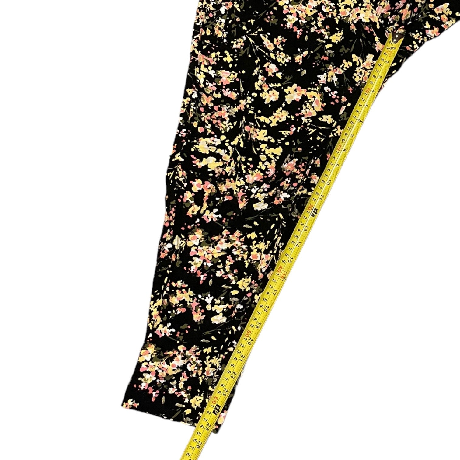 Floral-patterned fabric on a black background with a measuring tape for scale.