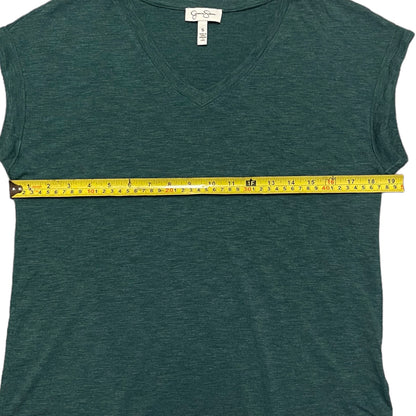 Green short sleeve shirt with a yellow measuring tape laying across it on a white background