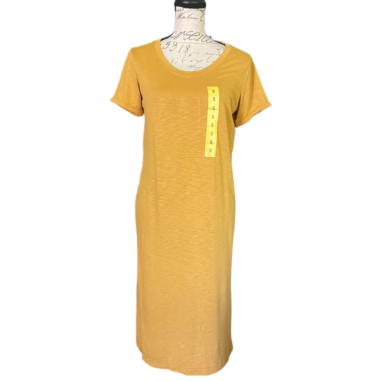 A mustard yellow short-sleeve t-shirt dress displayed on a dress form mannequin against a white background. 