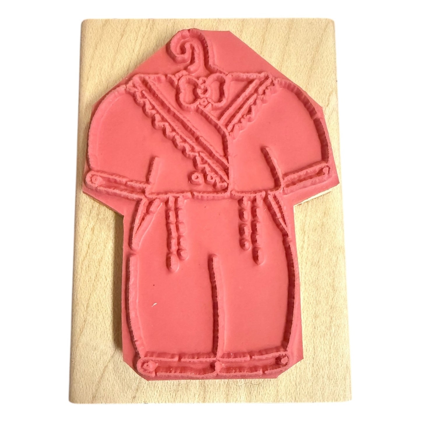 A pink rubber stamp featuring a detailed design of a baby outfit, mounted on a rectangular light wood block against a plain white background.