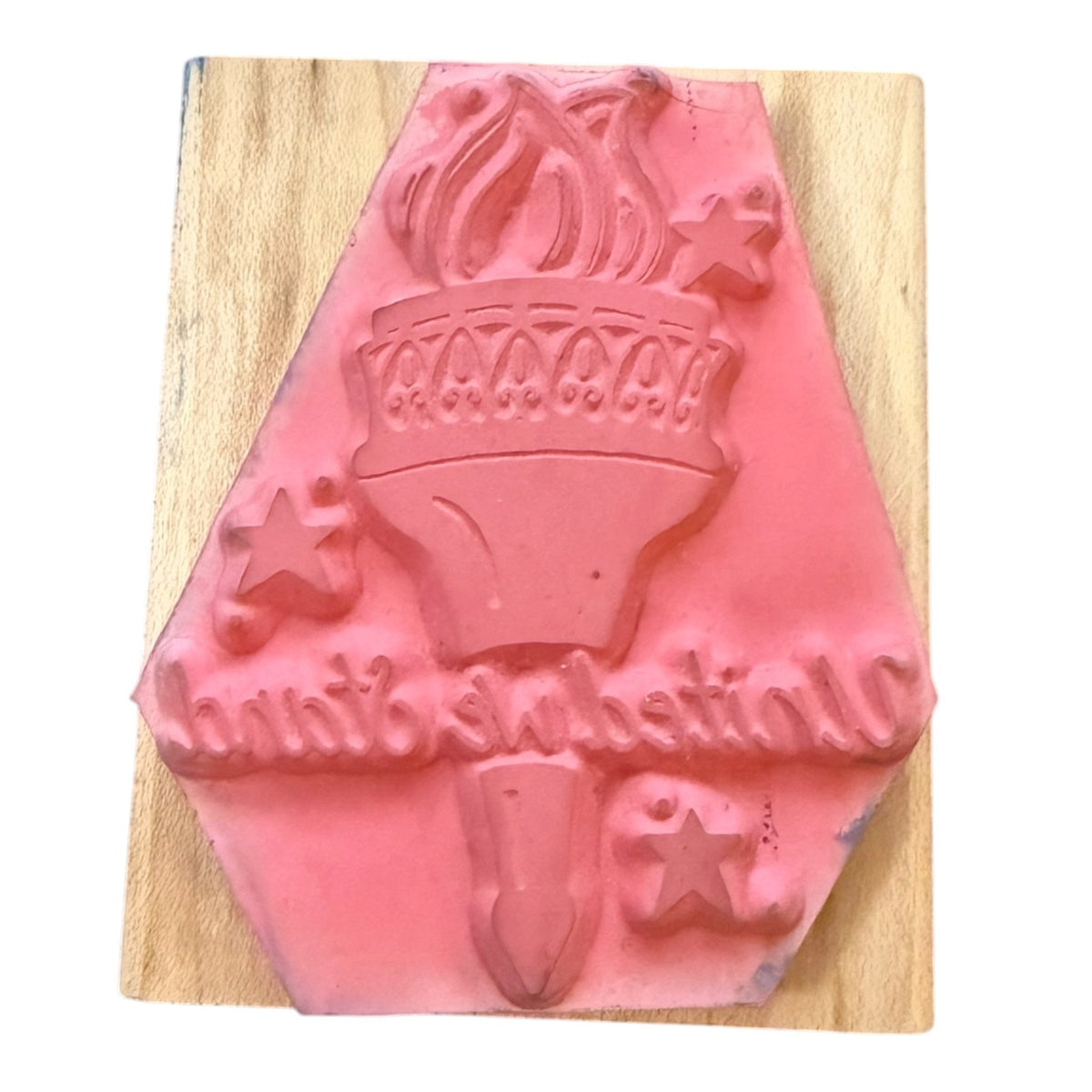 Pink rubber stamp on a wood block on a white background. 