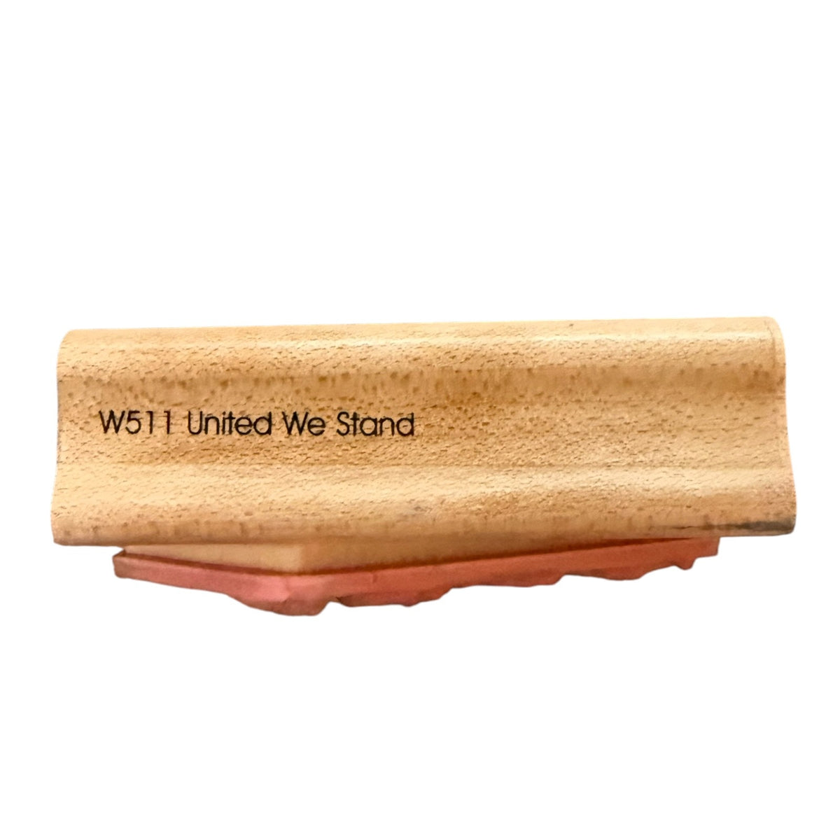 A wooden block stamp with the text 'W511 United We Stand' on a light wood surface, resting on a reddish-brown rubber base against a plain white background.