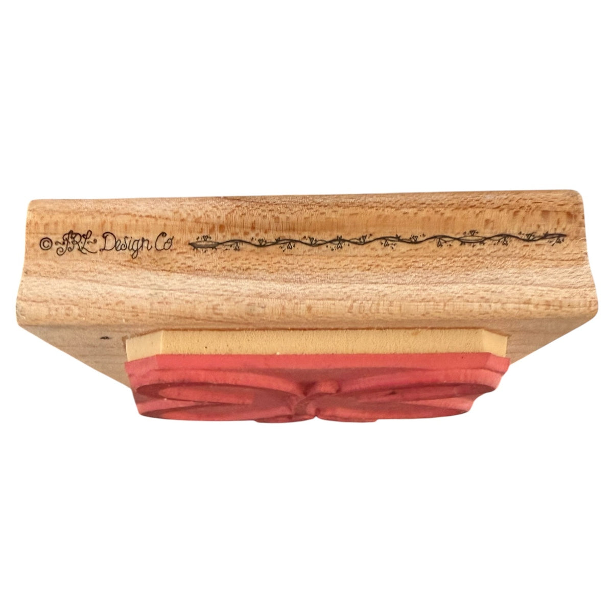 A wooden stamp block with a red rubber stamp , shown against a plain white background. The wood has 'JRL Design Co' on it.